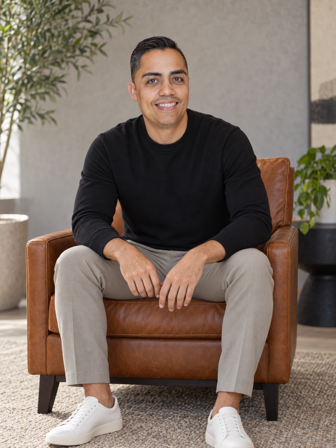 Eric Algarín seated in a leather armchair wearing a black sweater