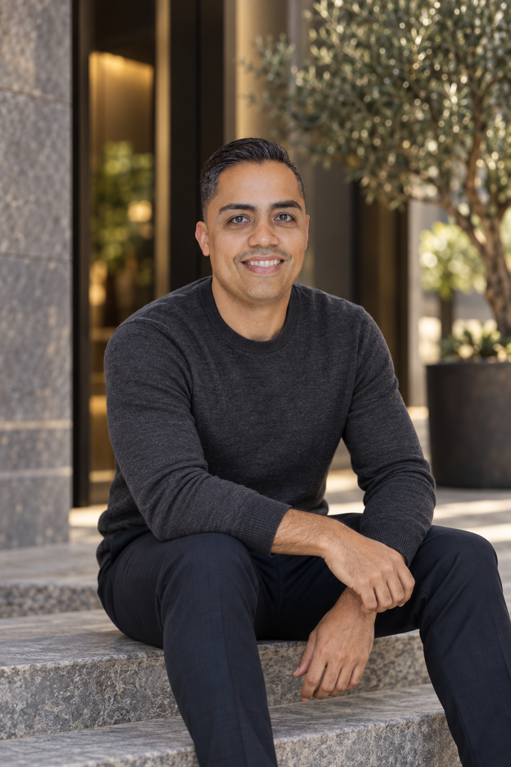 Eric in a charcoal sweater seated in a courtyard